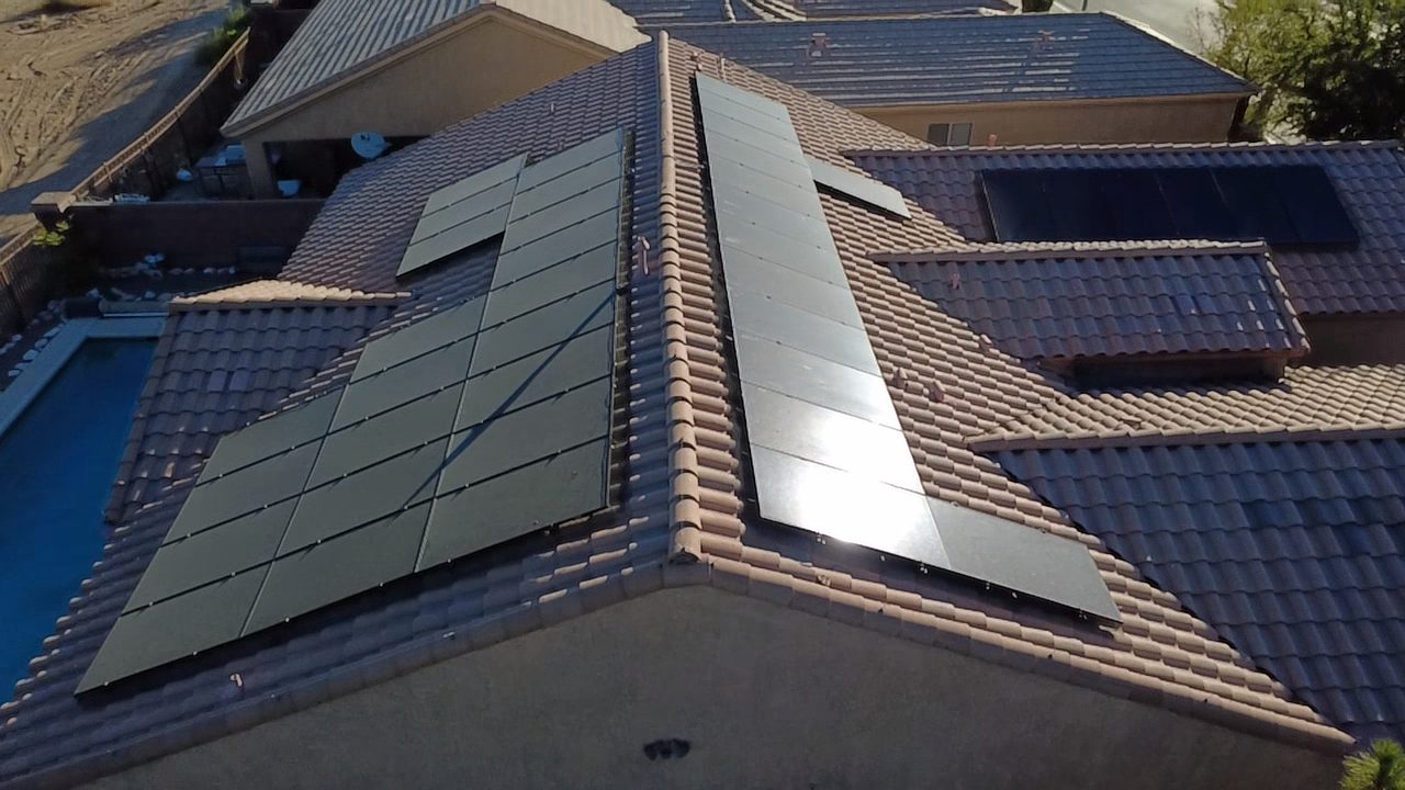 Angled aerial of residential solar array beside backyard pool